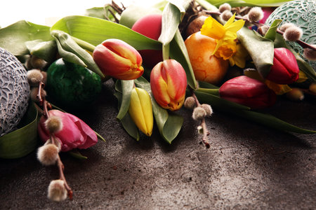Easter eggs and tulips and daffodils on rustic background. Springtime decoration for easter