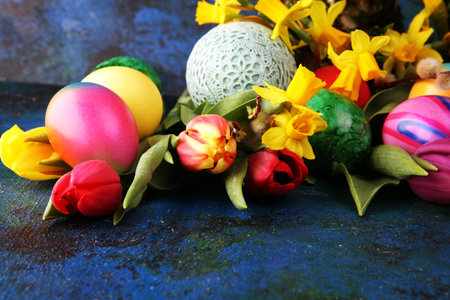Easter eggs and tulips and daffodils on rustic background. Springtime decoration for easter