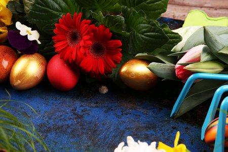 Easter eggs hiding in the grass with daffodil, tulips and other colorful spring flowers
