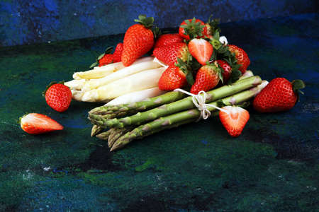 White and green fresh asparagus with a bunch of healthy strawberriesの写真素材