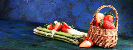 White and green fresh asparagus with a bunch of healthy strawberriesの写真素材