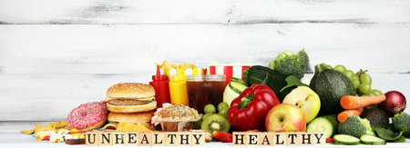healthy or unhealthy food. Concept photo of healthy and unhealthy food. Fruits and vegetables vs donuts,sweets and burgers on tableの写真素材