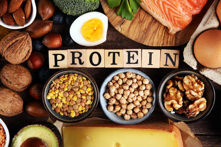 healthy eating and diet concept - natural rich in protein food on table with wooden letter protein