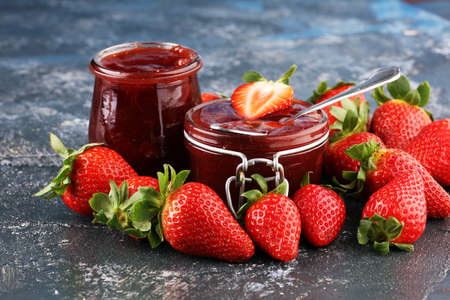 Strawberry jam in a glass jar with strawberries and leaves on rustic background. Homemade strawberry marmelade and fruitsの写真素材