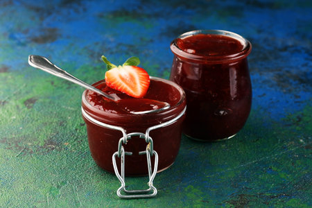 Strawberry jam in a glass jar with strawberries and leaves on rustic background. Homemade strawberry marmelade and fruitsの写真素材