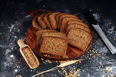 Sliced rye bread on cutting board. Whole grain rye bread with seeds on rustic background