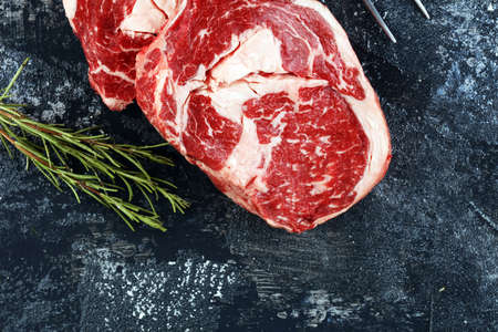 Two fresh raw rib-eye steak with rosmary in a rustic style backgroundの写真素材