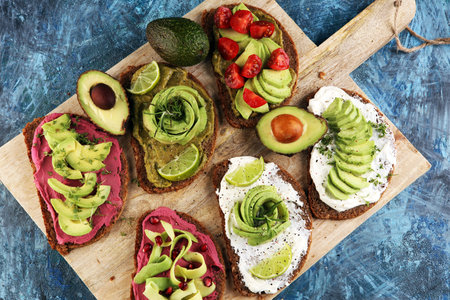 Avocado toast. Variation of healthy rye breakfast sandwiches with avocado and toppings like tomato...