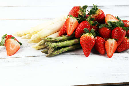 White and green fresh asparagus with a bunch of healthy strawberriesの写真素材