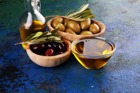 Bottle virgin olive oil and oil in a bowl with some olives.の写真素材