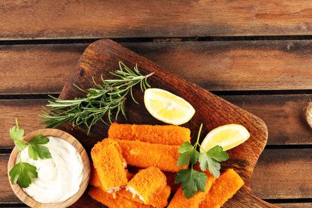 fresh fish fingers with remoulade sauce. breaded fish fingers with lemon