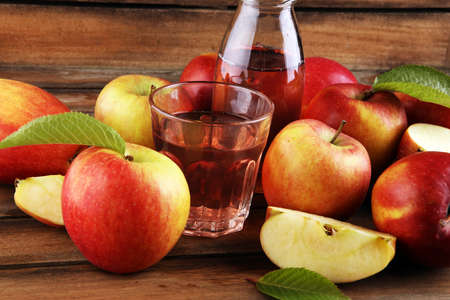 Apple cider drink and apples with leaves on rustic tableの写真素材