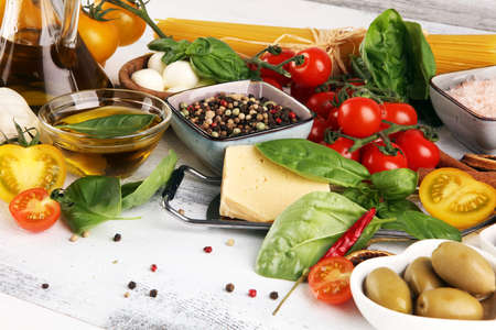 Italian food background with herbs and spices, vine tomatoes, basil, spaghetti, olives, parmesan, olive oil, garlic, peppercorns and rosemaryの写真素材