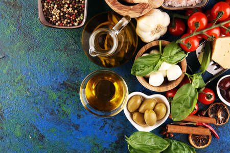 Italian food background with herbs and spices, vine tomatoes, basil, spaghetti, olives, parmesan, olive oil, garlic, peppercorns and rosemaryの写真素材