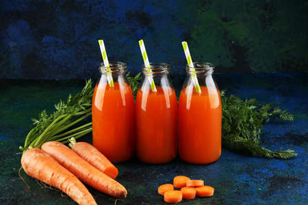 Fresh carrot juice in bottles with organic carrots on rustic tableの写真素材