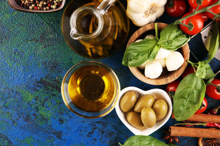 Italian food background with herbs and spices, vine tomatoes, basil, spaghetti, olives, parmesan, olive oil, garlic, peppercorns and rosemaryの写真素材