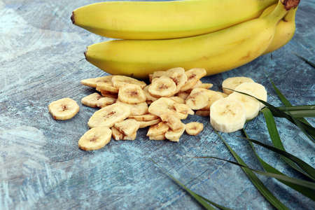 Homemade Dehydrated Banana Chips and fresh banana and slices on tableの写真素材