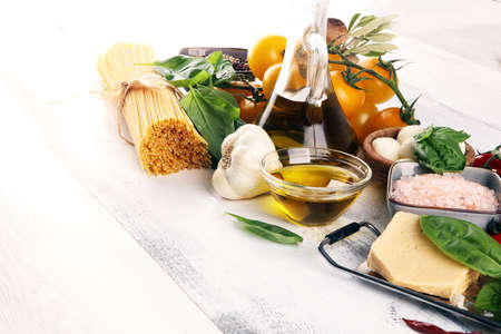 Italian food background with herbs and spices, vine tomatoes, basil, spaghetti, olives, parmesan, olive oil, garlic, peppercorns and rosemaryの写真素材