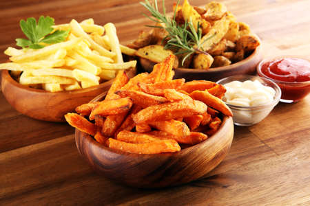 Variety of potatoes with fries. potato wedges, french fries, sweet potato for lunch on backgroundの写真素材