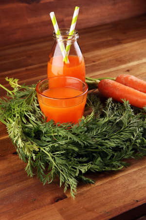 Fresh carrot juice in bottles with organic carrots on rustic tableの写真素材