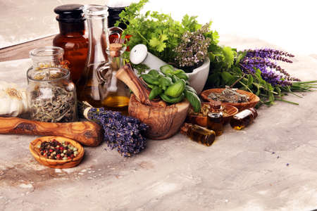 Fresh herbs in mortar bowl from the garden and the different types of oils for massage and aromatherapy.の写真素材