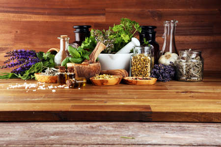 Fresh herbs in mortar bowl from the garden and the different types of oils for massage and aromatherapy.の写真素材