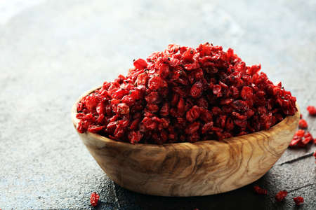 Pile of dry barberries in bowl on rustic backgroundの写真素材
