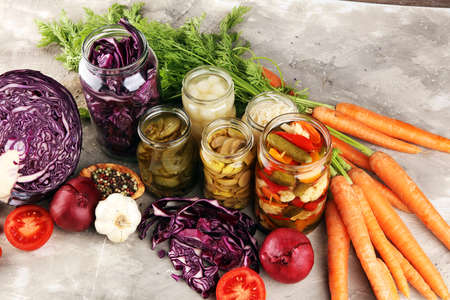 Preserves vegetables in glass jars. Pickled Cucumber, carrot, fermented cabbage and onions on rustic tableの写真素材