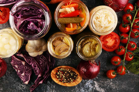 Preserves vegetables in glass jars. Pickled Cucumber, carrot, fermented cabbage and onions on rustic tableの写真素材