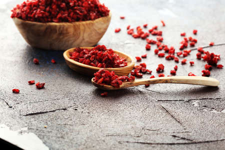 Pile of dry barberries in bowl on rustic backgroundの写真素材