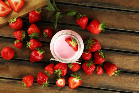 Glass of fresh strawberry yogurt and fresh strawberries on table. Healthy food and drink concept with juicy fruits and dairy fresh dessertの写真素材