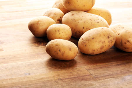 Pile of potatoes lying on wooden boards. Fresh potato on rustic backgroundの写真素材