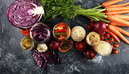 Preserves vegetables in glass jars. Pickled Cucumber, carrot, fermented cabbage and onions on rustic tableの写真素材