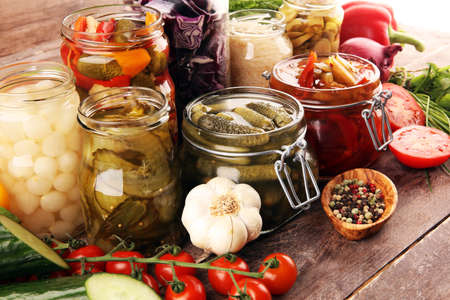 Preserves vegetables in glass jars. Pickled Cucumber, carrot, fermented cabbage and onions on rustic tableの写真素材