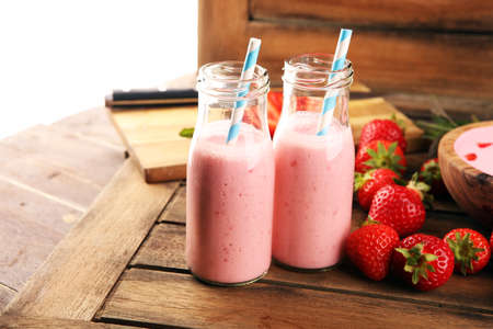 Glass of fresh strawberry shake, smoothie or milkshake and fresh strawberries on table. Healthy food and drink concept with juicy fruits の写真素材