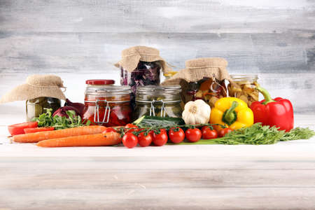 Preserves vegetables in glass jars. Pickled Cucumber, carrot, fermented cabbage and onions on rustic tableの写真素材