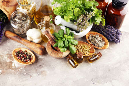 Fresh herbs in mortar bowl from the garden and the different types of oils for massage and aromatherapy.の写真素材