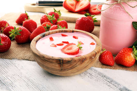 Glass of fresh strawberry yogurt and fresh strawberries on table. Healthy food and drink concept with juicy fruits and dairy fresh dessertの写真素材