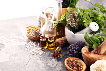 Fresh herbs in mortar bowl from the garden and the different types of oils for massage and aromatherapy.の写真素材