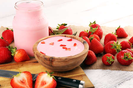 Glass of fresh strawberry yogurt and fresh strawberries on table. Healthy food and drink concept with juicy fruits and dairy fresh dessertの写真素材