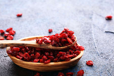 Pile of dry barberries in bowl on rustic backgroundの写真素材