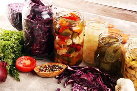 Preserves vegetables in glass jars. Pickled Cucumber, carrot, fermented cabbage and onions on rustic tableの写真素材