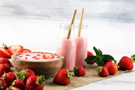 Glass of fresh strawberry shake, smoothie or milkshake and fresh strawberries on table. Healthy food and drink concept with juicy fruits の写真素材