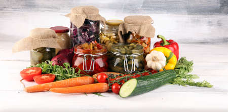 Preserves vegetables in glass jars. Pickled Cucumber, carrot, fermented cabbage and onions on rustic tableの写真素材