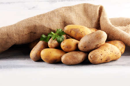 Pile of potatoes lying on wooden boards. Fresh potato on rustic backgroundの写真素材