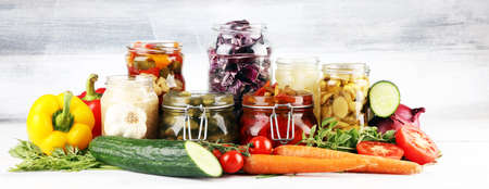 Preserves vegetables in glass jars. Pickled Cucumber, carrot, fermented cabbage and onions on rustic tableの写真素材