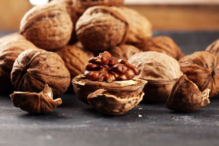Walnut kernels and whole healthy walnuts on rustic old tableの写真素材