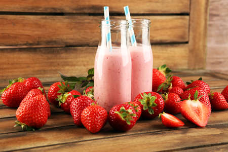 Glass of fresh strawberry shake, smoothie or milkshake and fresh strawberries on table. Healthy food and drink concept with juicy fruits の写真素材