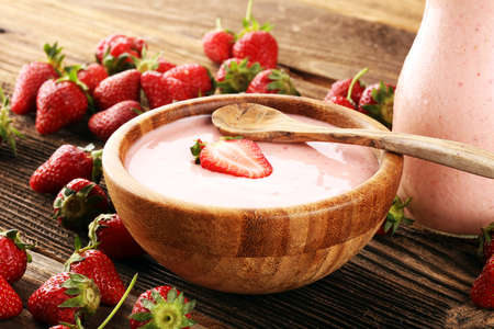 Bowl of fresh strawberry yogurt and fresh strawberries on table. Healthy food and drink concept with juicy fruits and dairy fresh dessertの写真素材