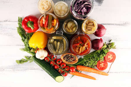 Preserves vegetables in glass jars. Pickled Cucumber, carrot, fermented cabbage and onions on rustic tableの写真素材